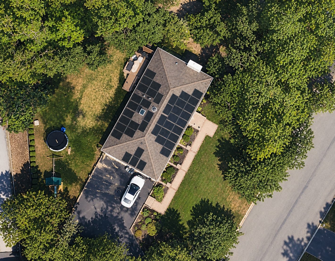 Aerial view of a Wading River home with rooftop solar surrounded by trees