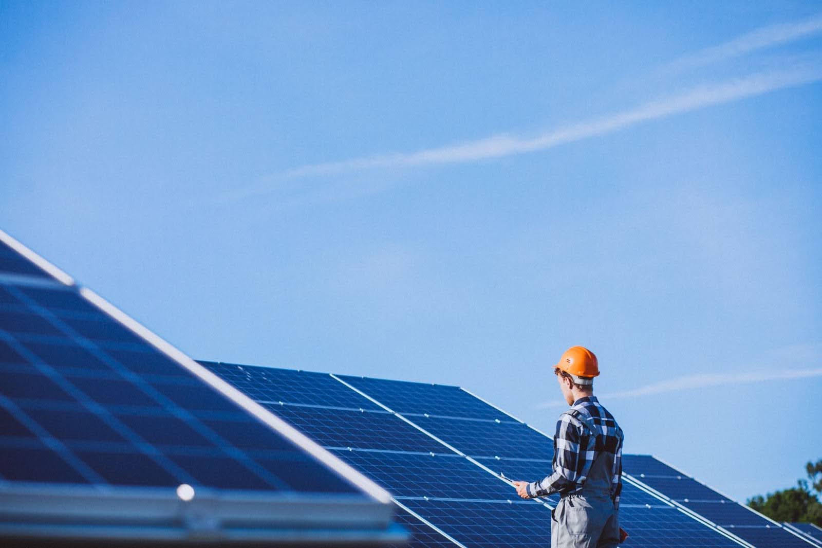 123z A professional inspecting solar panels in a commercial area. To get a free estimate for solar panel installation, contact us today.<br />