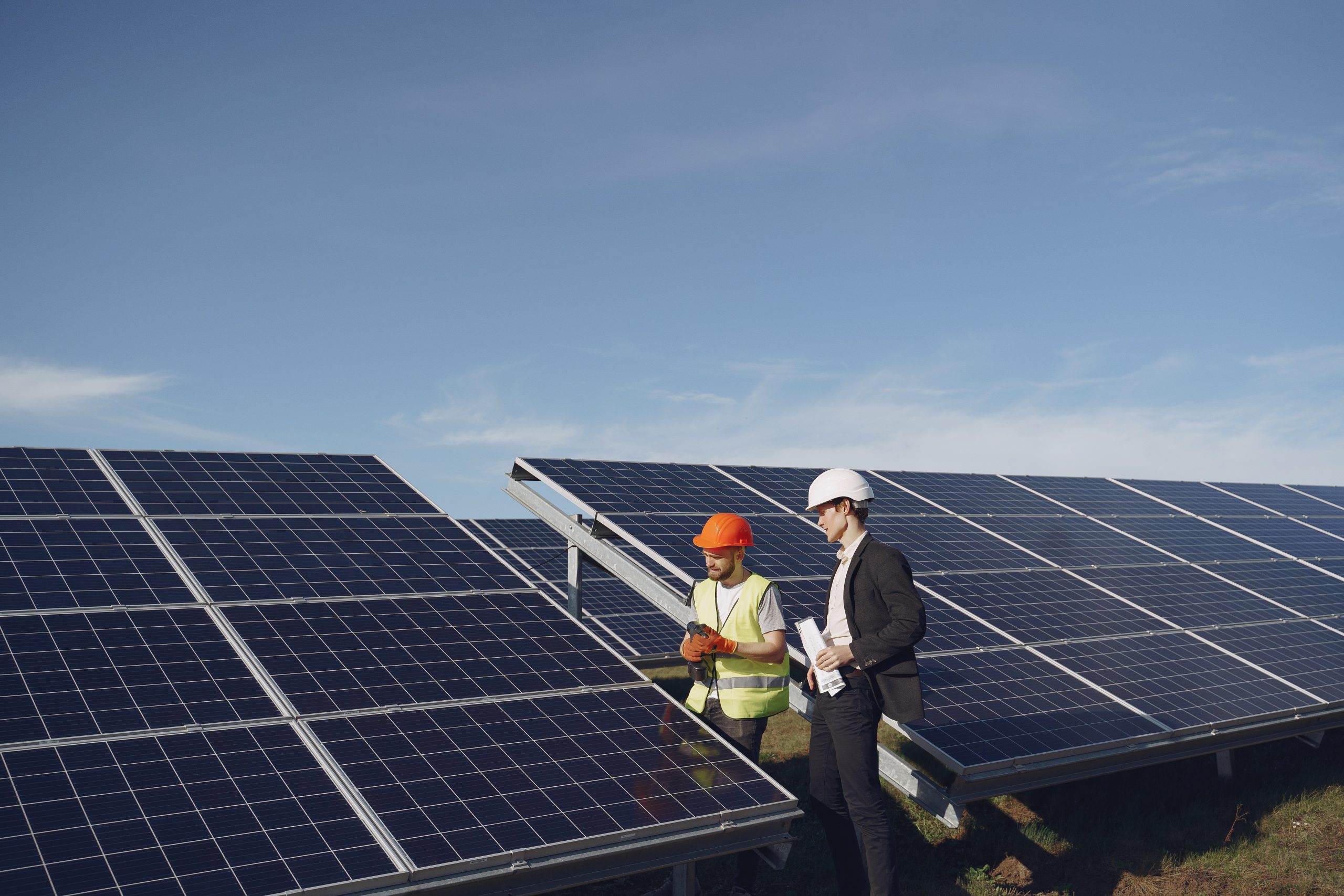 Foreman and businessman at solar energy station. Solar experts examining newly installed solar panels in a commercial area. To get an estimate, get in touch with us now.<br />
