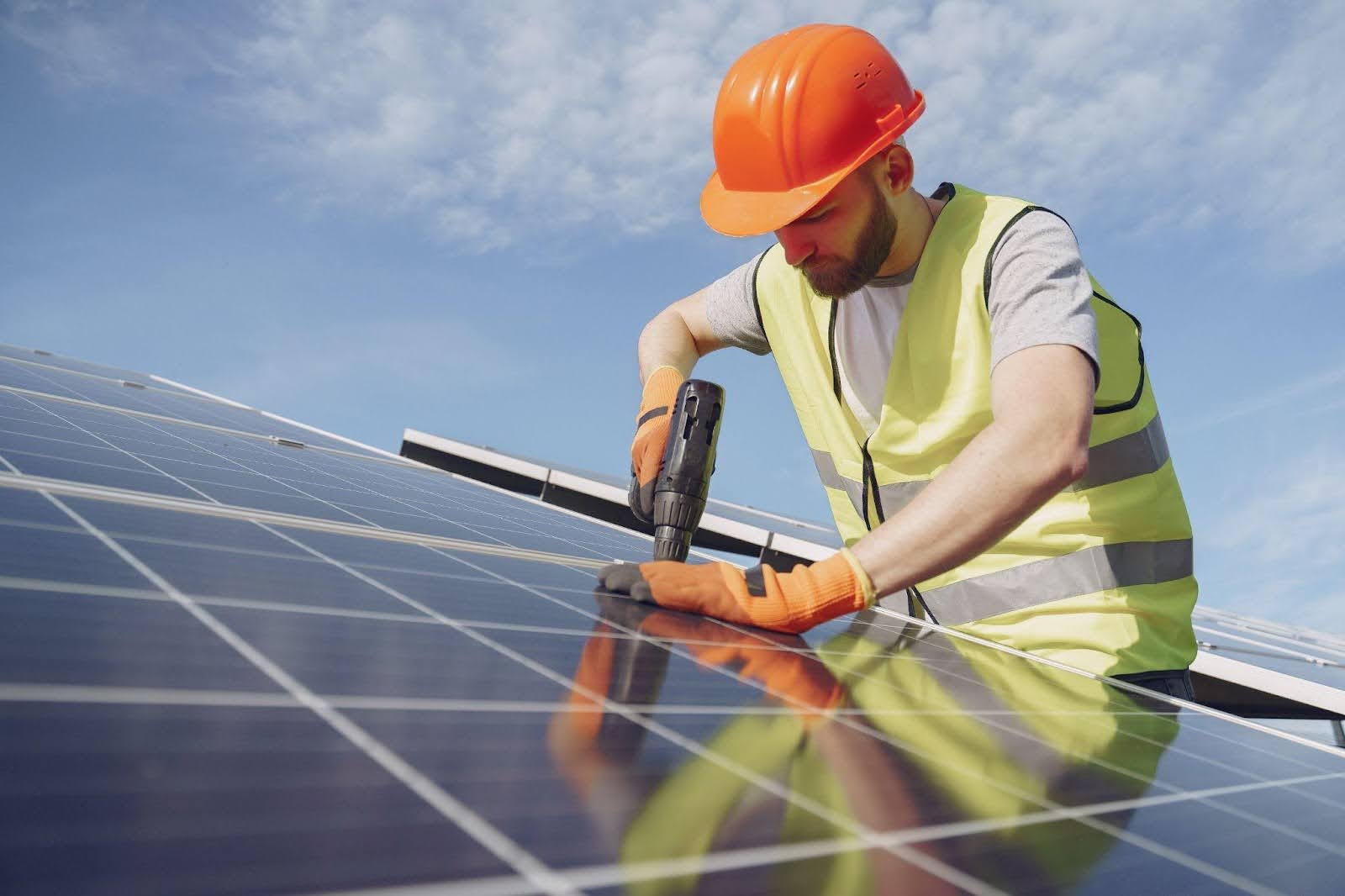 jioo Solar installer working for one of the best solar companies in Belle Terre, NY, while installing a solar panel on the roof of a building<br />